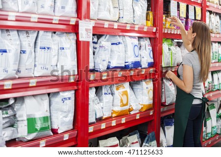 Saleswoman Arranging Food Packages In Pet Store