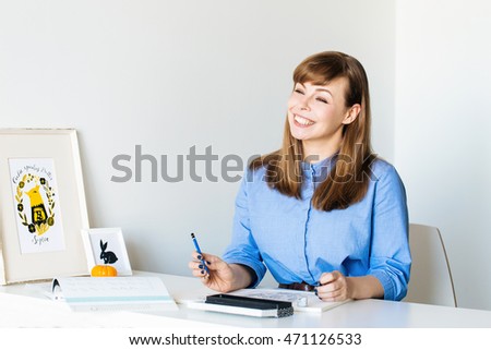 Beautiful smiling young woman illustrator at work, looking forward
