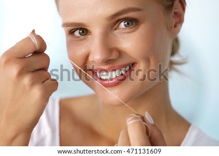 Dental Health. Closeup Portrait Of Beautiful Happy Smiling Young Woman With Perfect Smile Cleaning Healthy White Teeth, Flossing Using Floss. Tooth Care, Oral Hygiene Concept. High Resolution Image