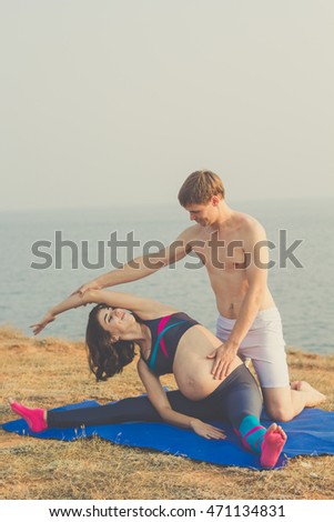 Pregnant girl and man are doing stretching
