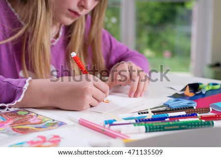 Hands of cute blonde girl drawing on a paper.