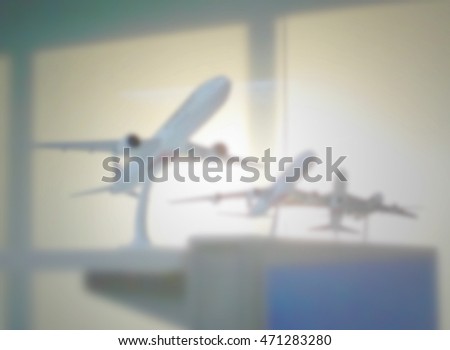 Light blue airplane model, blur aircraft background, sunset outside office window