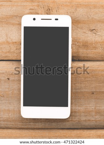 white smart phone on wooden background with copy space,top view.
