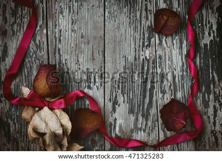 Dry red rose, silk ribbon bow on old wooden table