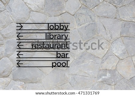 Hotel arrow signage on stone wall background. Lobby, Library, restaurant, bar and pool sign.