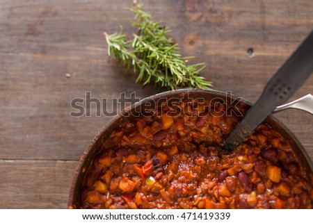 Organic Vegetarian Chili In Iron Pot Served With Rosemary On Distressed Wood Country Table. Royalty-Free Stock Photo #471419339