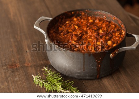 Organic Vegetarian Chili In Iron Pot Served With Rosemary On Distressed Wood Country Table.