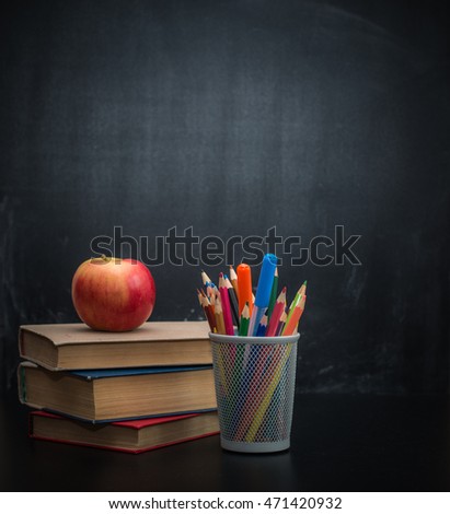 Background blackboard chalk, books, colored pencils and an apple