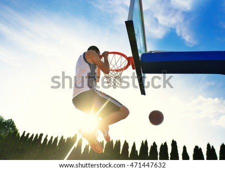 Street basketball player performing power slum dunk