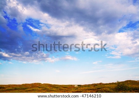 Dark grey clouds in blue sky under the tundra by day in summer