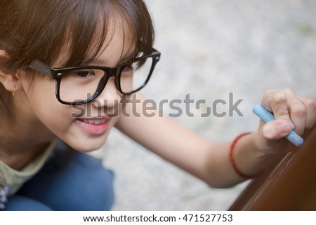 Happy Asian student girl writing on the blackboard