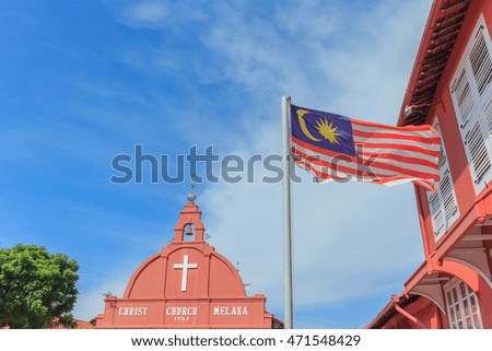 Malaysian national flag on a pole against blue sky on christ church melaka background