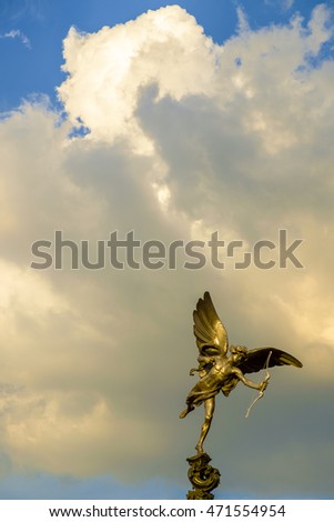 Close up on bronze statue resembling Cupid shooting off an arrow from his bow in dramatic partly cloudy sky with copy space