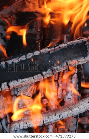 Charred wood and bright flames on dark background