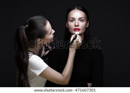 Two beautiful girls on a photo shoot to apply makeup to the face. Beauty fashion model. Photos shot in studio