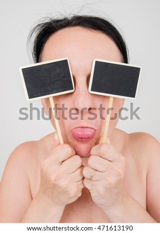 woman holding two black board signs on sticks to cover eyes, sticking her tongue out. Copy space on the blank signs.