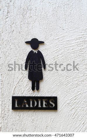 Woman metal restroom sign on gray cement wall