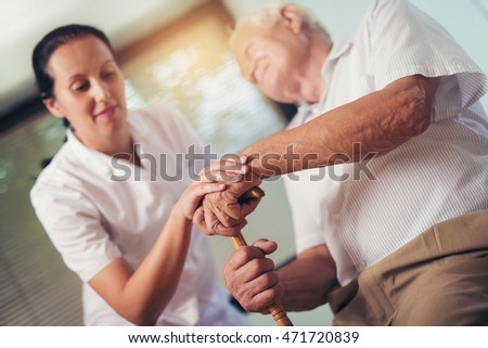 Young woman holding hand of old man with walking stick Royalty-Free Stock Photo #471720839