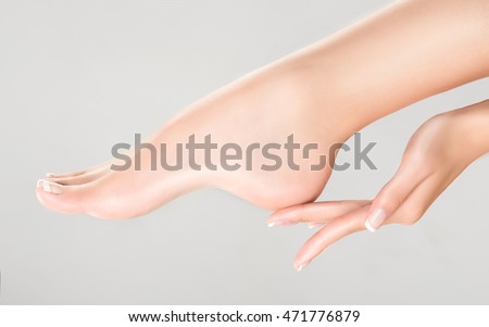 Perfect clean female feet . Beautiful and elegant groomed girl's hand touching  her foot . Spa ,scrub and foot care . Royalty-Free Stock Photo #471776879