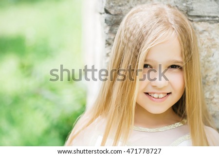 small girl kid with long blonde hair and pretty smiling happy face in white dress sunny day outdoor on blurred green background, closeup