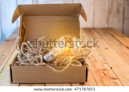 Opened brown paper box with turned on  light bulb inside / New idea concept / Unleashing your idea concept
