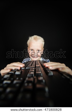 Smiling blond youth holds keyboard in both hands against a black background