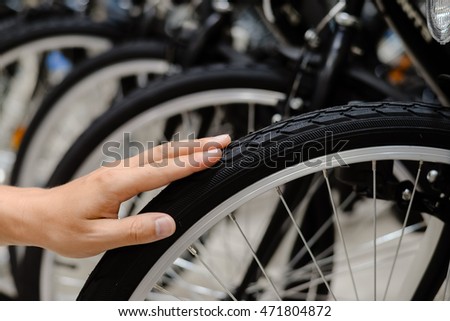 Closeup on person hand checking bicycle tire, shop factory background.