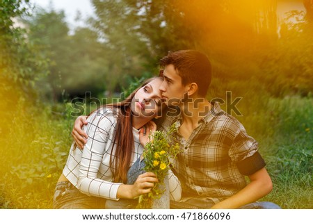 Enamoured teens together. Girlfriend and boyfriend together. The boy hugs a girl. A girl holding a bouquet of wildflowers. Creative shooting. First love. He falls in love. Date.