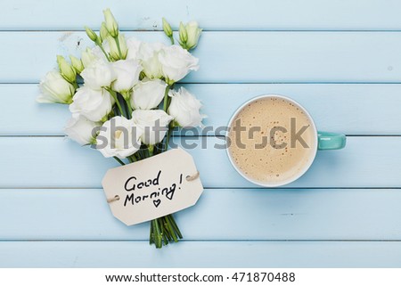 Coffee mug with white flowers and notes good morning on blue rustic table from above. Beautiful breakfast. Flat lay.