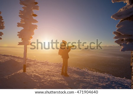 Male photographer on top of the mountain, photographed the sunset. Near the pillars direction signs. Wide angle. Silhouette.