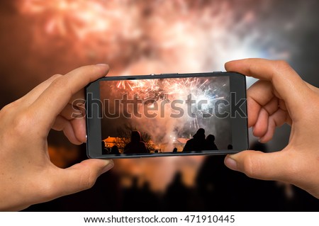 Woman hands with mobile cell phone to take a photo of fireworks