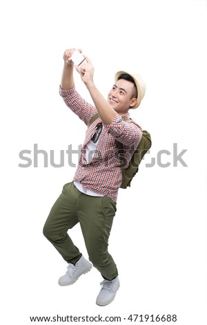 Portrait of smiling asian man taking selfie on white background with backpack taking a photo