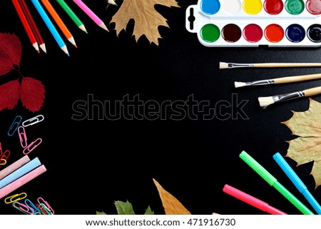 Paints, pencils and brushes on blackboard
