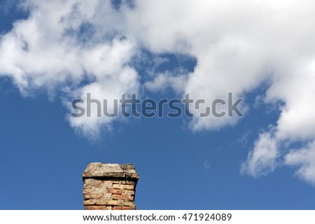 Old brick chimnet against blue sky with clouds. Background for design and ideas.