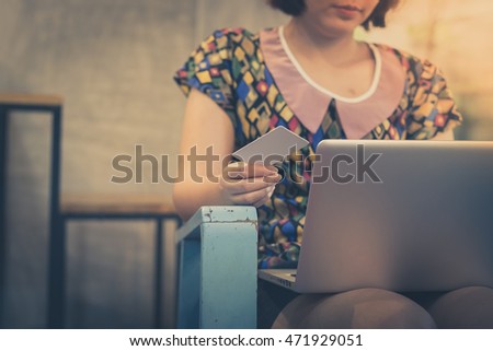 Woman holding credit card for electronic payment while using laptop for online shopping at home. E business and shopping at home concept with vintage filter effect