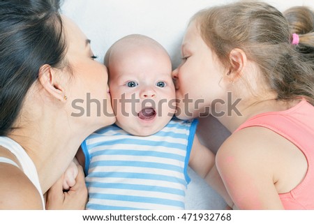 Happy family mother with daughter kissing baby. Newborn and child. Mothercare is most important in children life.