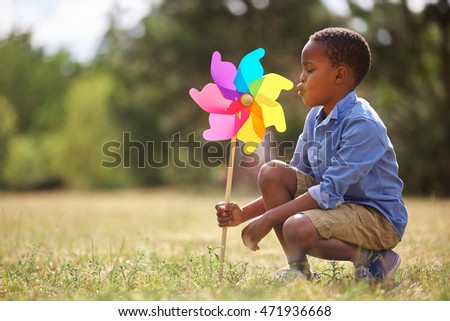 African kid playing with pinwheel at the park Royalty-Free Stock Photo #471936668