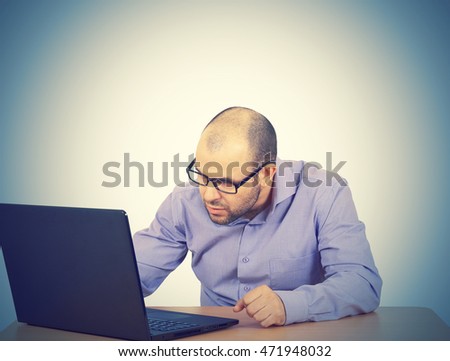 Funny photo of businessman bald with beard wearing shirt and glasses.  angry businessman working with laptop at table. Isolated on background 