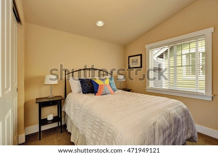 Vaulted ceiling bedroom interior in beige colors. Single bed with iron headboard and white bedding. Northwest, USA