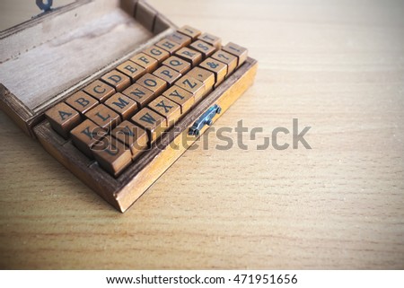 Alphabets stamp in the box on wooden background. Toned image.