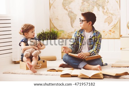 children brother and sister, boy and girl reading a book at home Royalty-Free Stock Photo #471957182