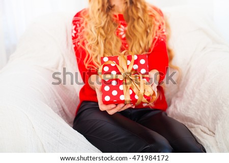 Female hands holding small red gift with ribbon.