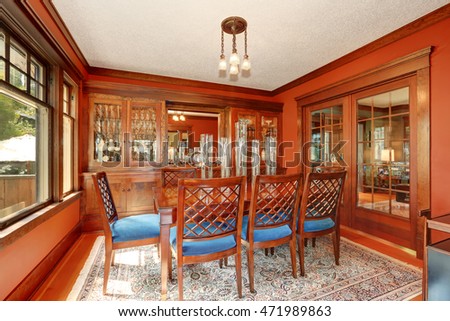 Red walls in dining room. Burgundy wooden table and carved chairs with blue seats. Northwest, USA
