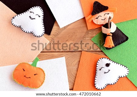 Halloween cute felt DIY. Homemade small witch with broom, pumpkin head, two ghosts. Halloween toys, colored felt pieces on wooden background with empty space for text. Autumn kids sewing crafts idea 