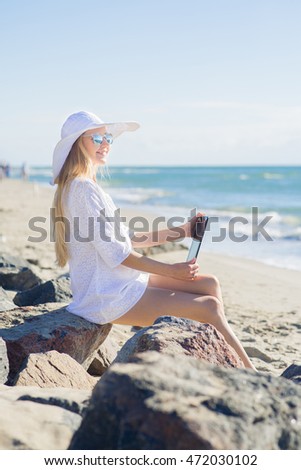 Young pretty woman in white with tablet on the beach