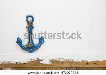 Blue anchor on old wooden white and brown background for concepts.