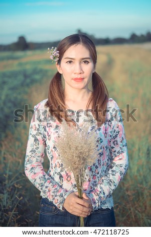 Beautiful woman holding flowers grass in hand and have a flowers at ear pastel tone,vintage,film,dark