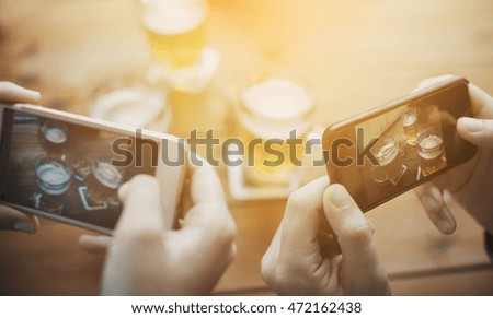 people and technology concept - close up of hands with smartphone picturing beer at bar