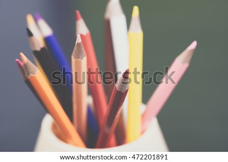Color pencils on the table in the container with background lights.  Colorful pencils in a variety of colors. Back to school concept. Toned picture.