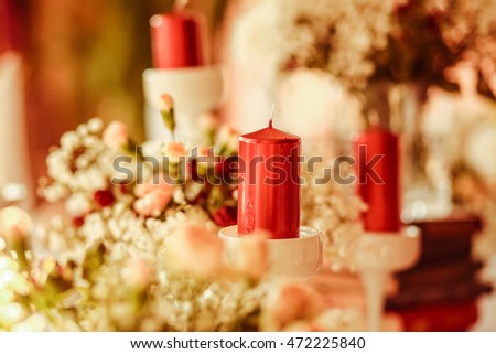 Wine red candle stands over the white bouquet on the dinner table